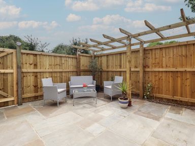 A garden with seating area and flower pot at Pear Tree Lodge in Alford