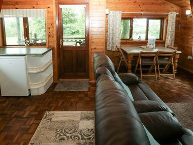 A living room with a sofa and a dining table at Oak Lodge in Mynydd Cerrig near Porthyrhyd