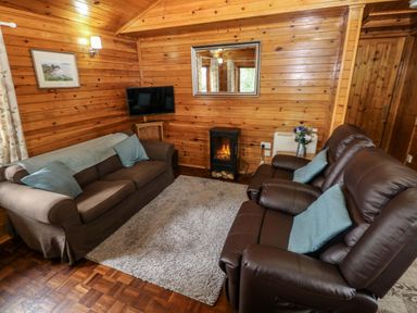 A living room with a sofa and armchair at Oak Lodge in Mynydd Cerrig near Porthyrhyd