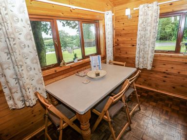 A dining room with a table and chairs at Oak Lodge near Mynydd Cerrig