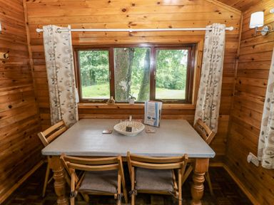 A dining room with a table and chairs at Oak Lodge Mynydd Cerrig near Porthyrhyd