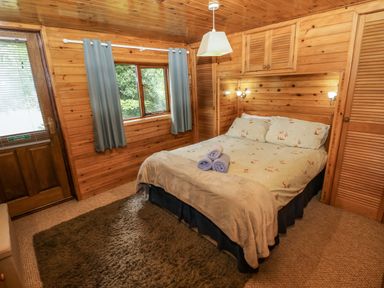 A bedroom with a bed and window at Oak Lodge near Mynydd Cerrig