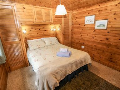 A bedroom with a bed and bedside lamps at Oak Lodge near Mynydd Cerrig