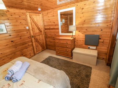 A bedroom with a bed and dressing table at Oak Lodge in Mynydd Cerrig near Porthyrhyd