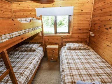 A bedroom with a bunk bed and a single bed at Oak Lodge near Mynydd Cerrig
