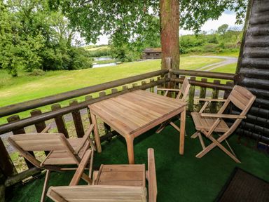 An outdoor area with a wooden table and chairs at Oak Lodge in Mynydd Cerrig near Porthyrhyd