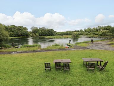 An outdoor area with a lake and fishing activity at Oak Lodge near Mynydd Cerrig