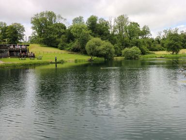 A lakeside scene with a fishing dock and trees at Oak Lodge Mynydd Cerrig near Porthyrhyd