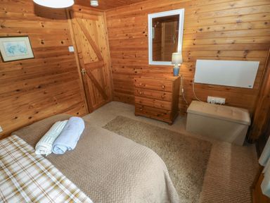 A bedroom with a bed and dresser at Ash Lodge Mynydd Cerrig near Porthyrhyd