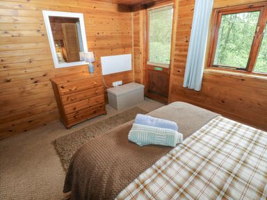 A bedroom with a bed and dresser at Ash Lodge in Mynydd Cerrig near Porthyrhyd