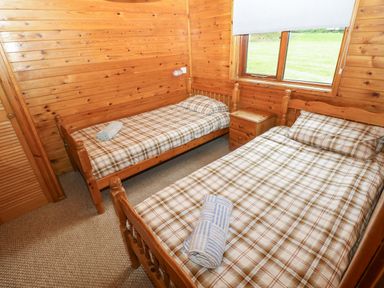 A bedroom with two single beds and a window at Ash Lodge in Mynydd Cerrig near Porthyrhyd