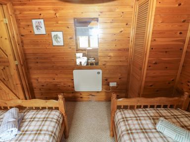 A bedroom with two beds and wooden walls at Ash Lodge near Mynydd Cerrig near Porthyrhyd