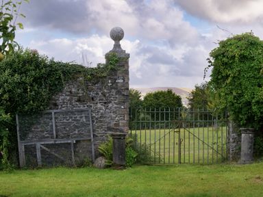A stone wall with a gate and trees at West Cottage in Llandovery
