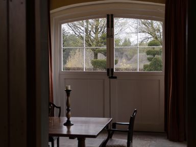 A window with a view of a garden and a table with a candle at West Cottage Myddfai near Llandovery
