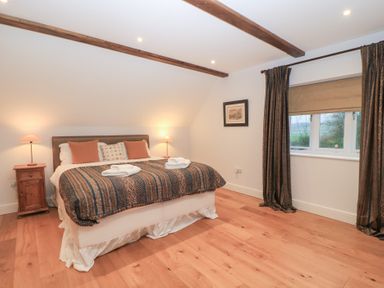 A bedroom with a bed and nightstand at Peewit Coach House in Moreton-in-Marsh