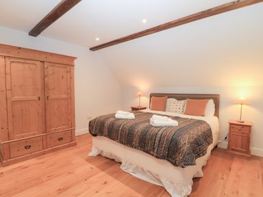 A bedroom with a bed and wardrobe at Peewit Coach House in Moreton-in-Marsh