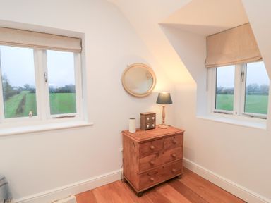 A bedroom with windows and a chest of drawers at Peewit Coach House in Moreton-in-Marsh