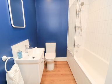A bathroom featuring a bathtub, toilet, sink, and mirror at Peewit Coach House in Moreton-in-Marsh
