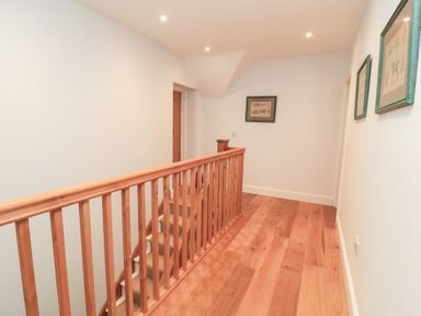 A hallway with a staircase and handrail at Peewit Coach House Moreton-in-Marsh