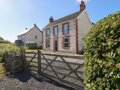 A house with a gate and hedge at Hawthorns in Swansea