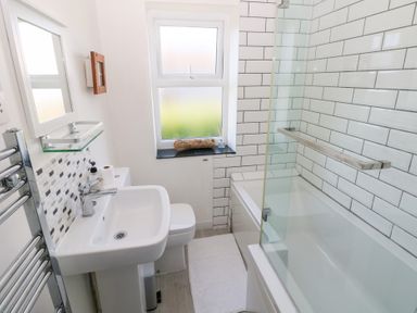 A bathroom with a bathtub, sink, and toilet at Hawthorns in Swansea