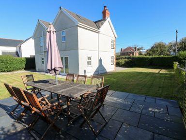 A garden with a dining table and chairs at Hawthorns in Swansea