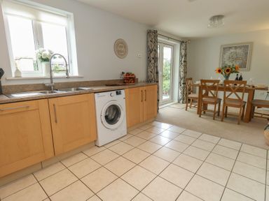 A kitchen with a wash machine and dining table at June Cottage in Wool