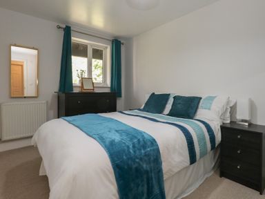A bedroom with a bed and a mirror at June Cottage in Wool