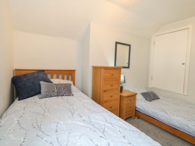 A bedroom with two beds and a dresser at June Cottage in Wool