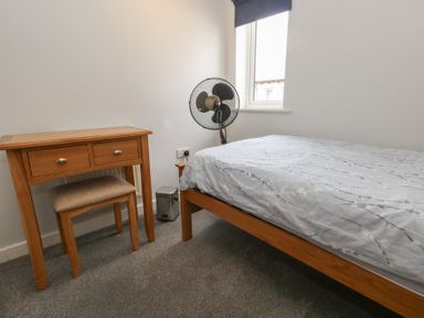 A bedroom with a bed, desk, and a fan at June Cottage in Wool