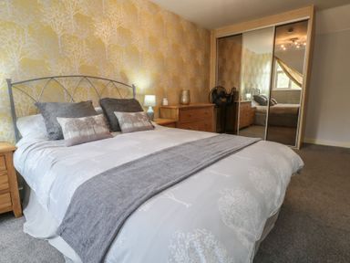 A bedroom with a bed and nightstand at June Cottage in Wool