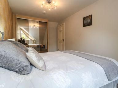 A bedroom with a bed and mirrored wardrobe at June Cottage in Wool