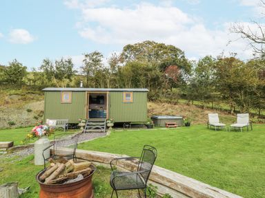 A garden with a shepherd's hut and a hot tub at Brondel Luxury Shepherd's Hut