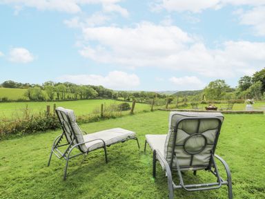 A garden with lounge chairs overlooking a green field at Brondel Luxury Shepherd's Hut