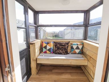 A snug area with wooden bench and cushions at Clawddcam in Mathry