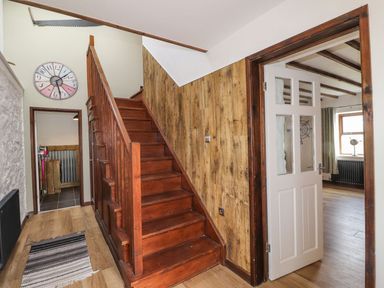 A hallway with a staircase and wall clock at Clawddcam in Mathry