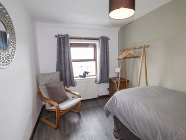 A bedroom with a bed and a chair at Clawddcam in Mathry
