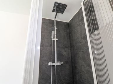 A shower area with a wall mounted shower head at Clawddcam in Mathry