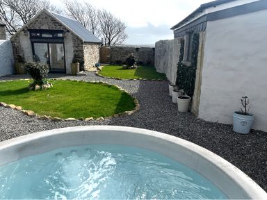 A garden with a hot tub and stone walls at Clawddcam Mathry