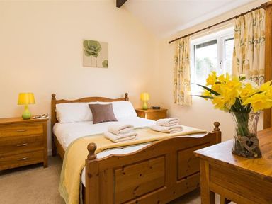A bedroom with a bed and flowers at 2 Riverside Cottages Ambleside