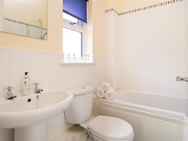 A bathroom with a wash basin, toilet, and bath at 2 Riverside Cottages in Ambleside