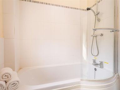 A bathroom with a bathtub and shower at 2 Riverside Cottages Ambleside
