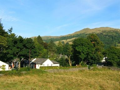 A view of houses and trees with mountains in the background at 2 Riverside Cottages Ambleside