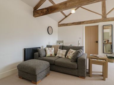 A living room with a sofa and side table at The Old Cart Shed in Gorsley