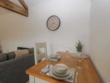 A dining area with a table set with dishes and a clock at The Old Cart Shed in Gorsley