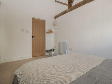 A bedroom with a bed and door at The Old Cart Shed Gorsley