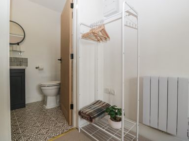 A bathroom with a toilet, sink, and clothes rack at The Old Cart Shed in Gorsley