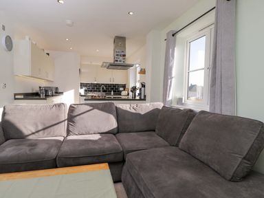 A living room with a sofa and kitchen area at Swallows Nest in Bourton-On-The-Water