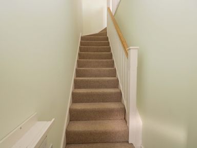 A staircase with carpet and a handrail at Swallows Nest in Bourton-On-The-Water