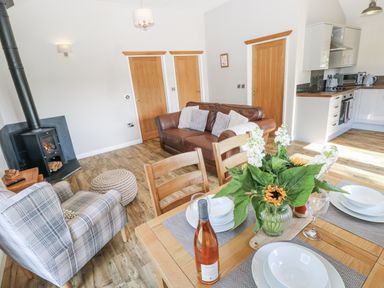 A living room with a sofa a dining table and kitchen appliances at Cadno in Llanybydder